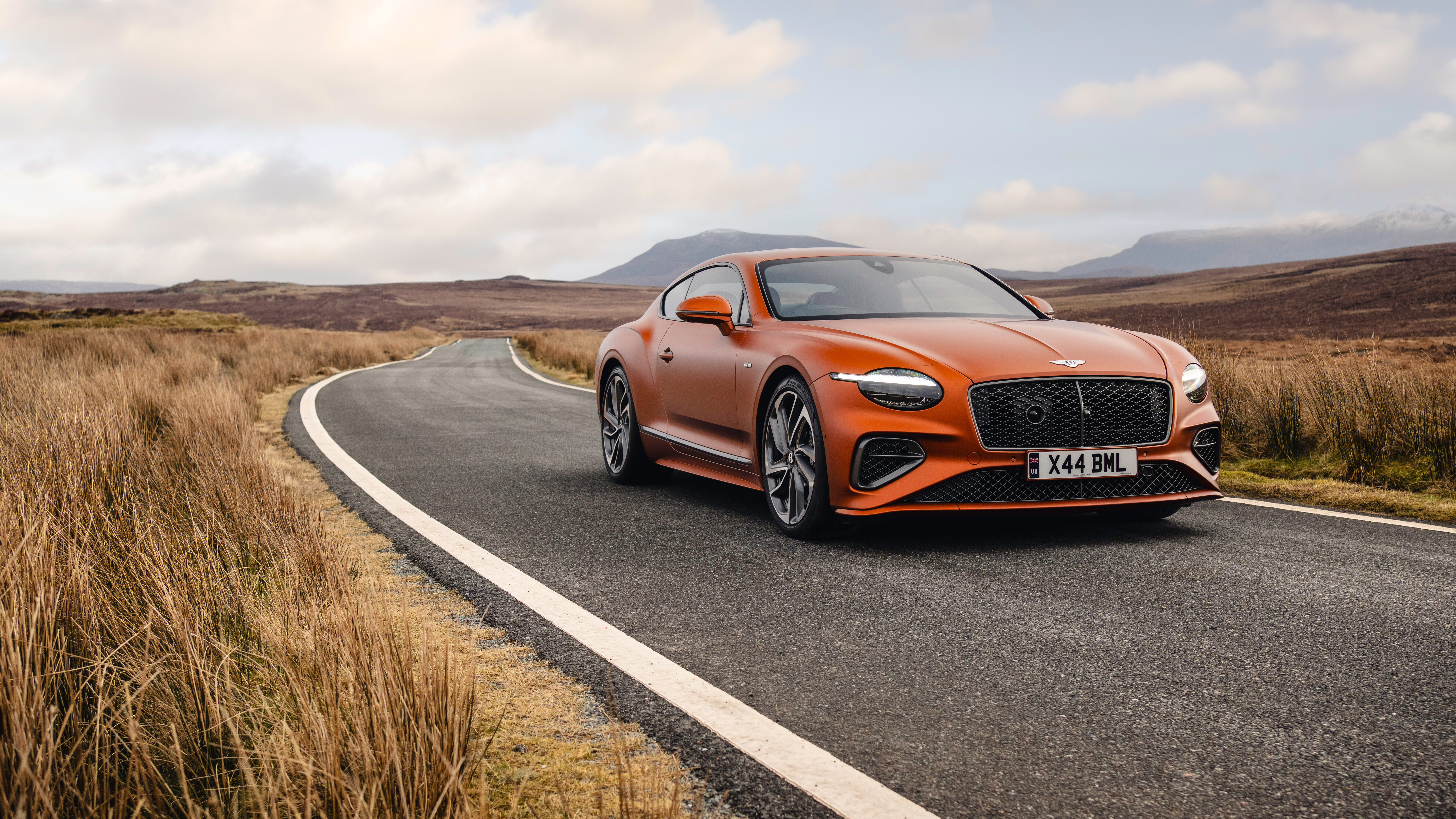 Une Bentley Continental GT Speed d’un orange éclatant, qui met en valeur son design luxueux et son allure imposante.