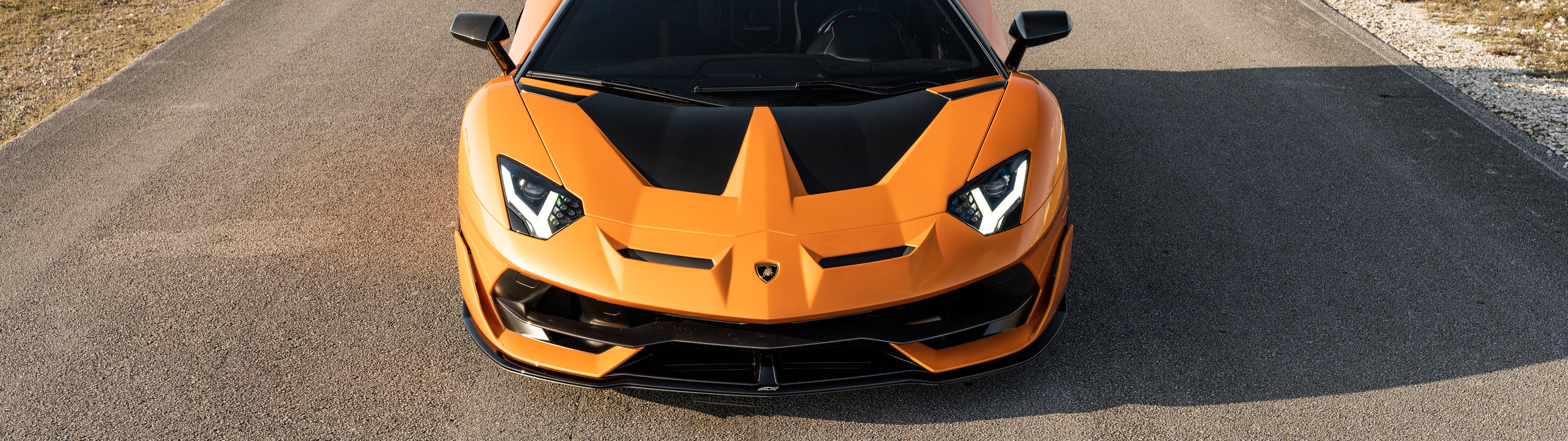 Une vue rapprochée d’une Lamborghini Aventador SVJ, mettant en valeur sa carrosserie aérodynamique élégante et la silhouette puissante de cette voiture de sport.